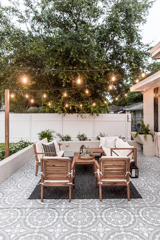 A tiled patio with dark rug, furniture, and string lights