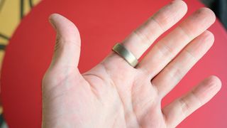 Amazfit Helio ring on a person's finger with a red background behind