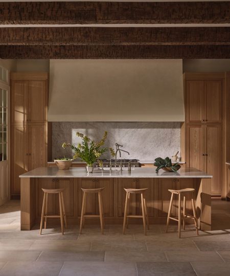 Wooden kitchen with large wooden island, wooden bar stools surrounding 