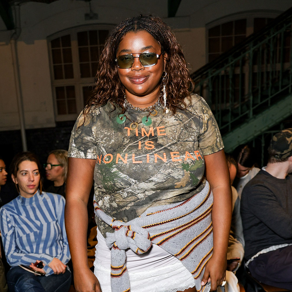  Gabriella Karefa-Johnson wearing a camo t-shirt with a white lace skirt and a striped gray sweater
