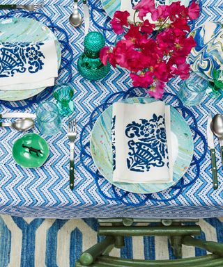 blue and white tablesetting with patterned cloth and colourful accessories