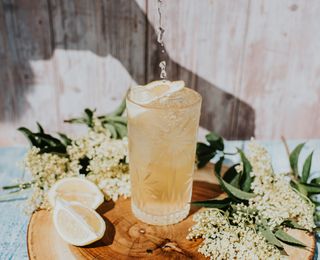 A lemon mocktail on a wooden board with blossom.