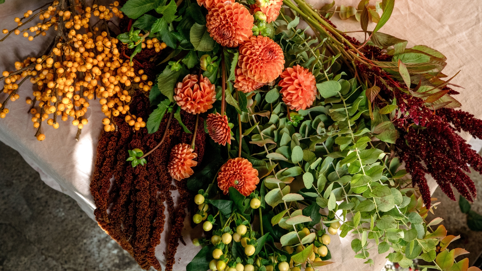 View of dahlias, orange berries burgundy amaranth, eucalyptus and cream hypericum