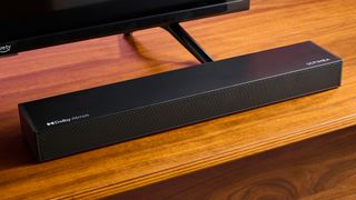 Ultimea Nova S50 soundbar on a wooden surface in front of a TV