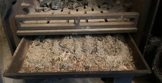 A close up of inside a log burner with a tray of ash to suggest how to clean log burner glass