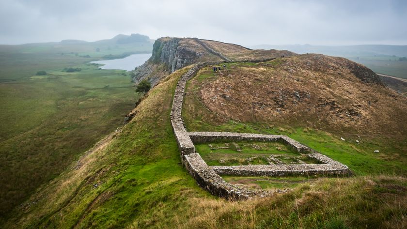 low wall on a hill stretching towards a cliff and the sea on an overcast day