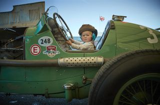 18-month-old Georgia Ricketts sits in a 1934 ERA R3A once driven by the famous racing driver Raymond Mays, which her father maintains and looks after, on day three of the Goodwood Revival Festival. Credit: Kiran Ridley/Getty Images