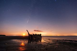 A bright-pink Perseid meteor shines above an old shipwreck on the coast of New Jersey in this photo by Jeff Berkes. He captured this photo early Sunday morning (Aug. 11), or about two days before the peak of the meteor shower.