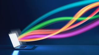 Multicoloured tendrils of light emanating from an open laptop