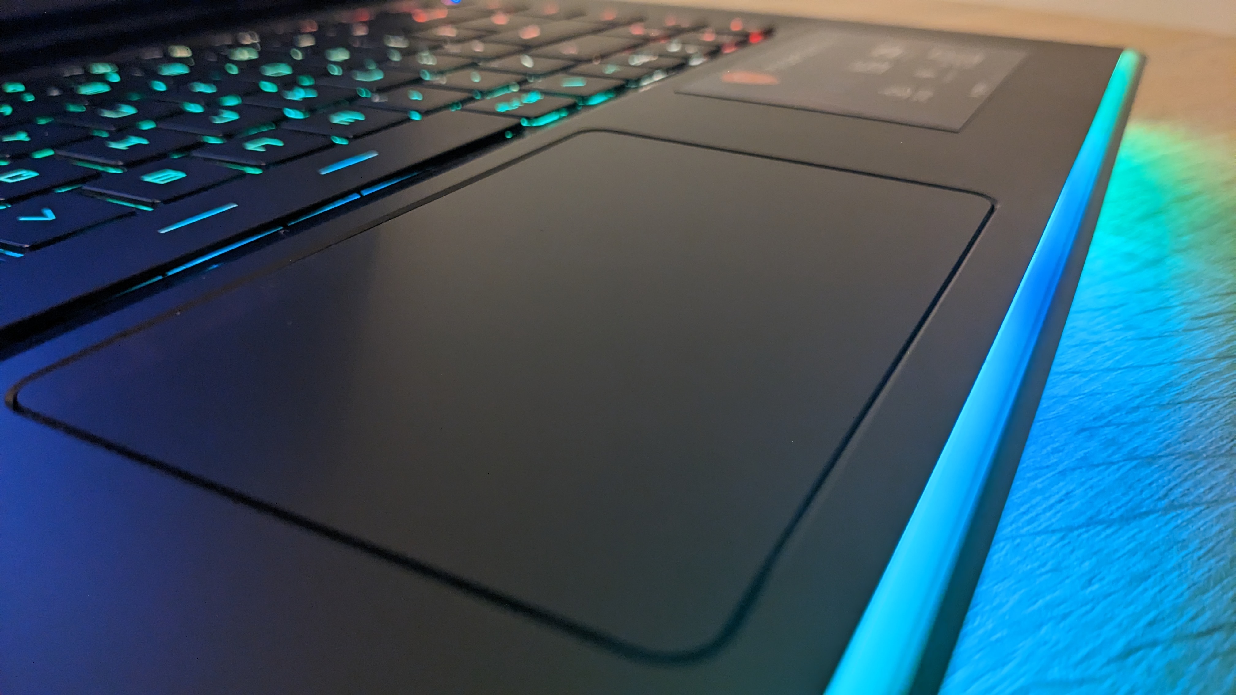 The MSI Raider GE67 HX photographed on a wooden desk with RGB lighting turned on.