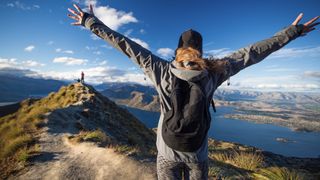 Woman raises hands in wonder at the mountains around her