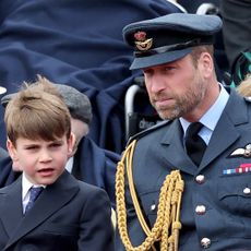 Prince Louis wearing a suit sitting next to Prince William, wearing a military uniform, at a VE Day parade