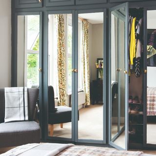 A bedroom with mirrored built-in wardrobes and a chair in the corner