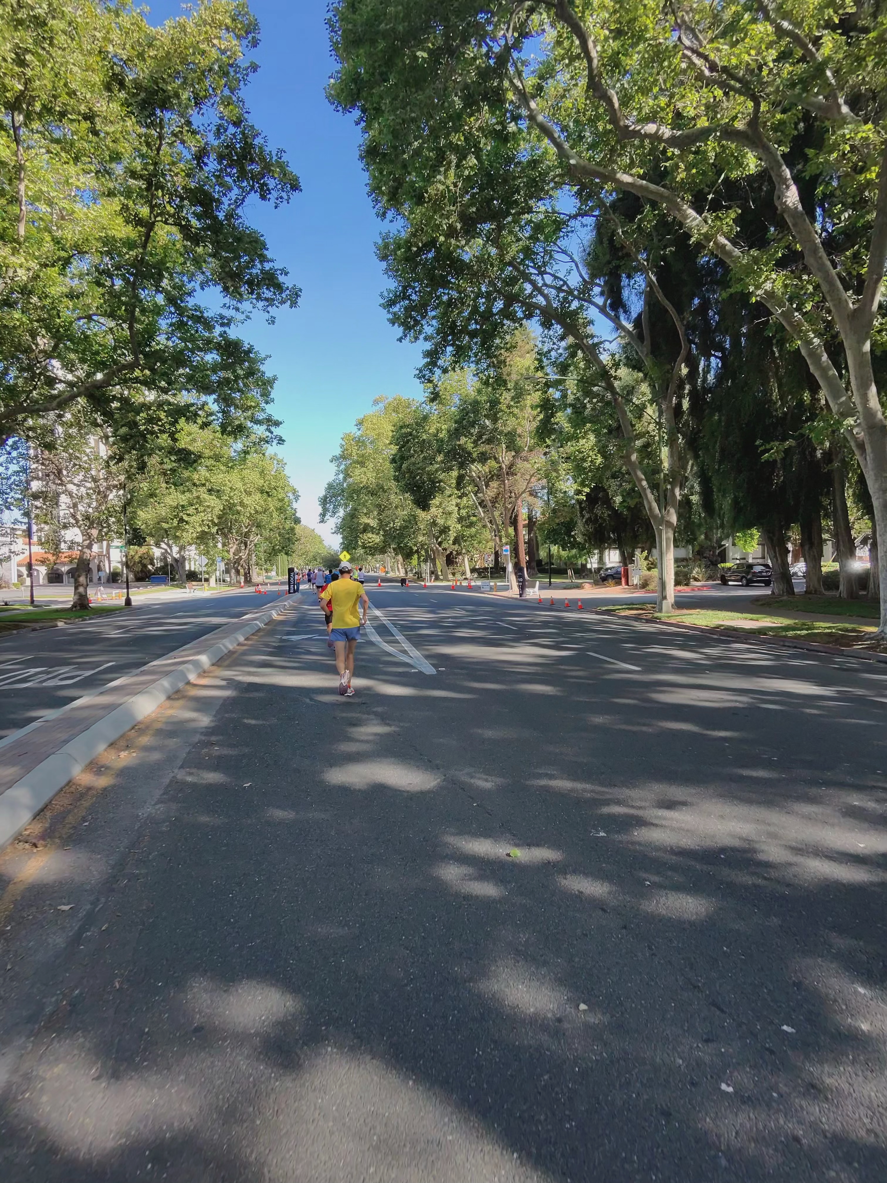 A Ray-Ban Meta smart glasses camera sample at the San Jose Half Marathon showing a tree-lined path with runners around.
