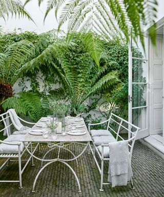 garden terrace with white table laid for lunch and chairs