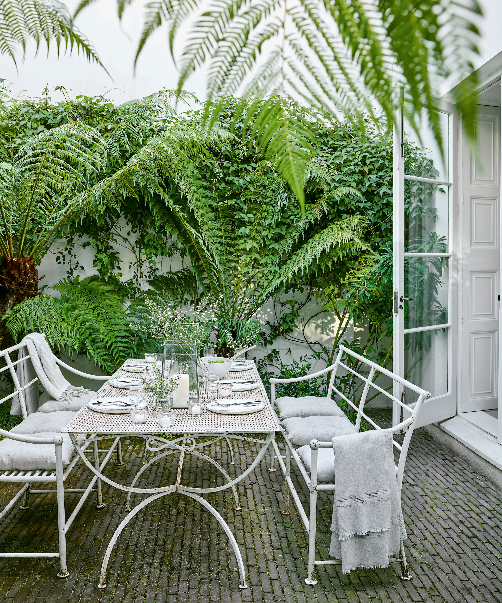 garden terrace with white table laid for lunch and chairs