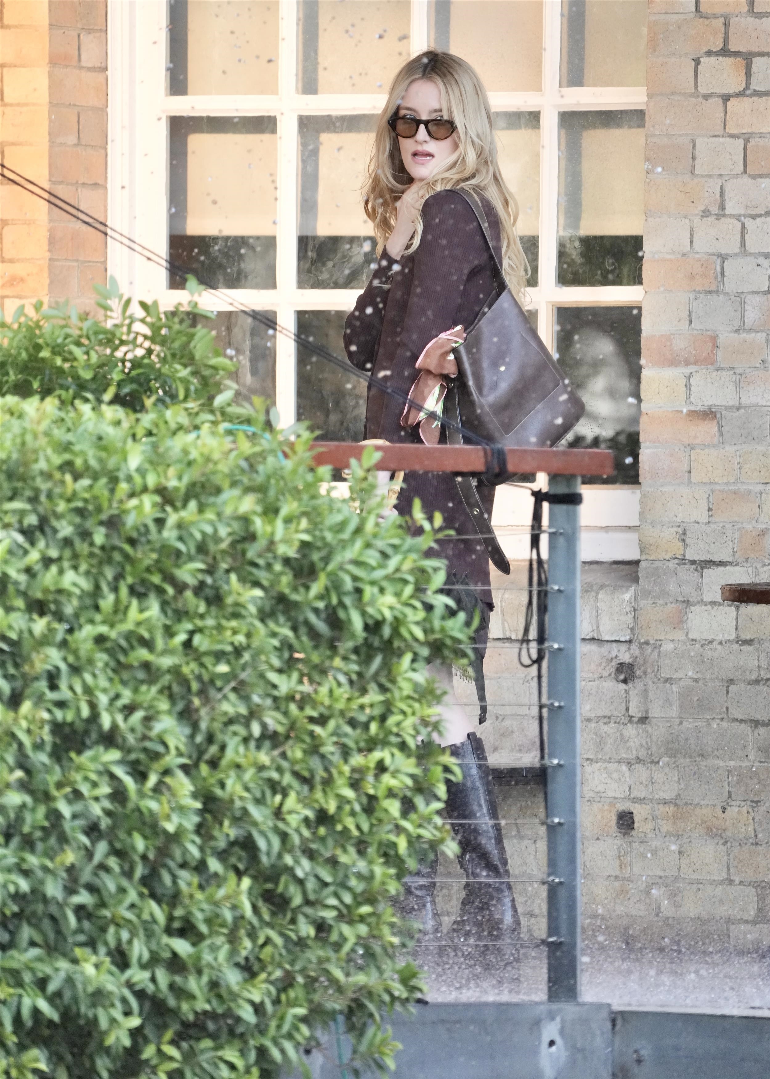 An image of Sarah Pidgeon wearing a knit dress and knee-high boots.