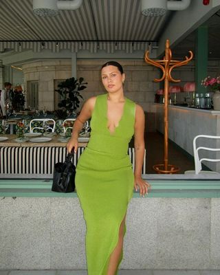 @isabellecoheen wearing a black handbag with a green dress