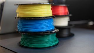 Several rolls of 3D printer filament stacked, each a different colour