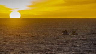 As the sun sets on the horizon, NASA's Recovery Team and the U.S. Navy practice recovering a test version of the Orion space capsule as part of Underway Recovery Test-7 (URT-7) in the Pacific Ocean on Nov. 1, 2018.