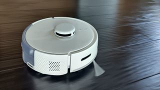 Switchbot robot vacuum on black floor