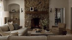 Neutral living room with a large stone fireplace and an arched alcove