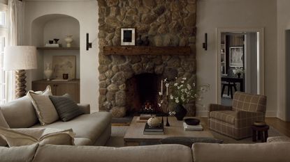 Neutral living room with a large stone fireplace and an arched alcove