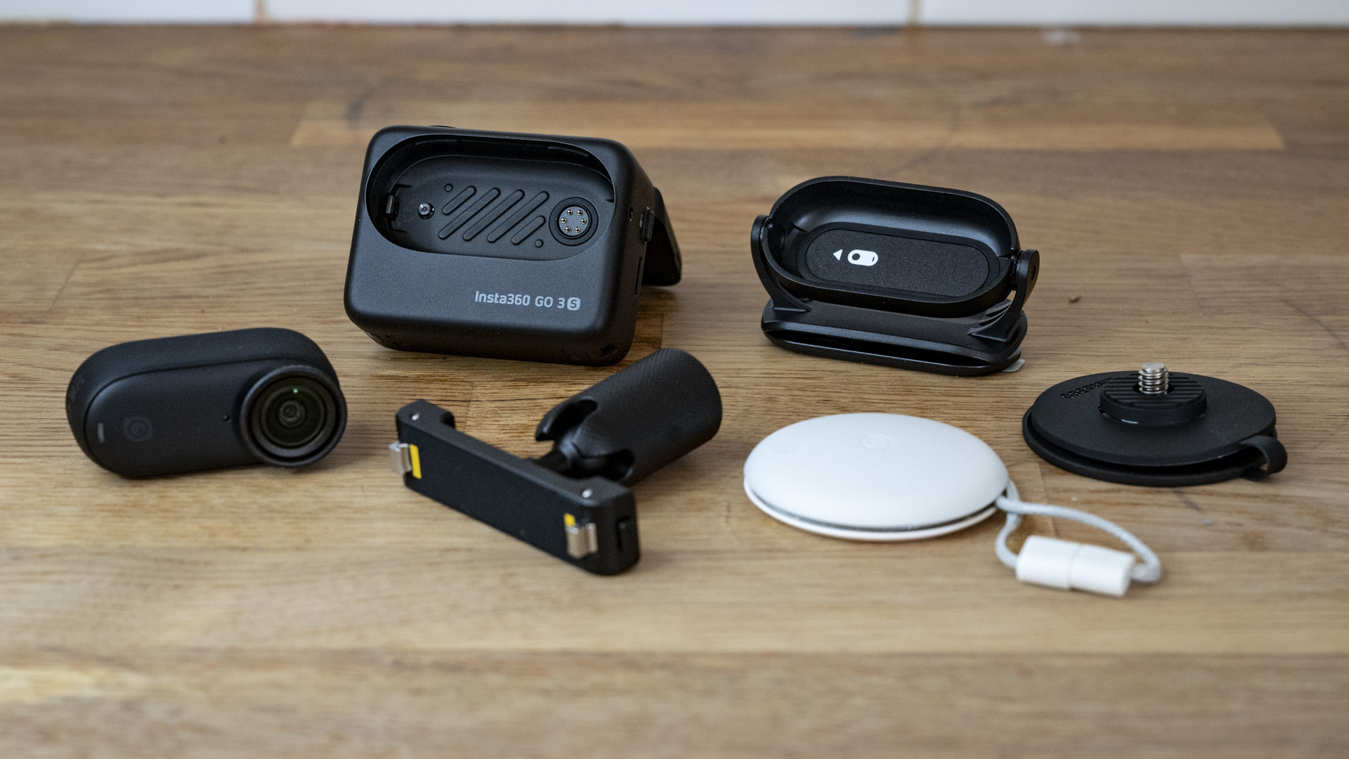 Insta360 Go 3S camera alongside all the supplied accessories on a wooden surface