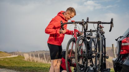 Male cyclist putting his bike onto a car bike rack