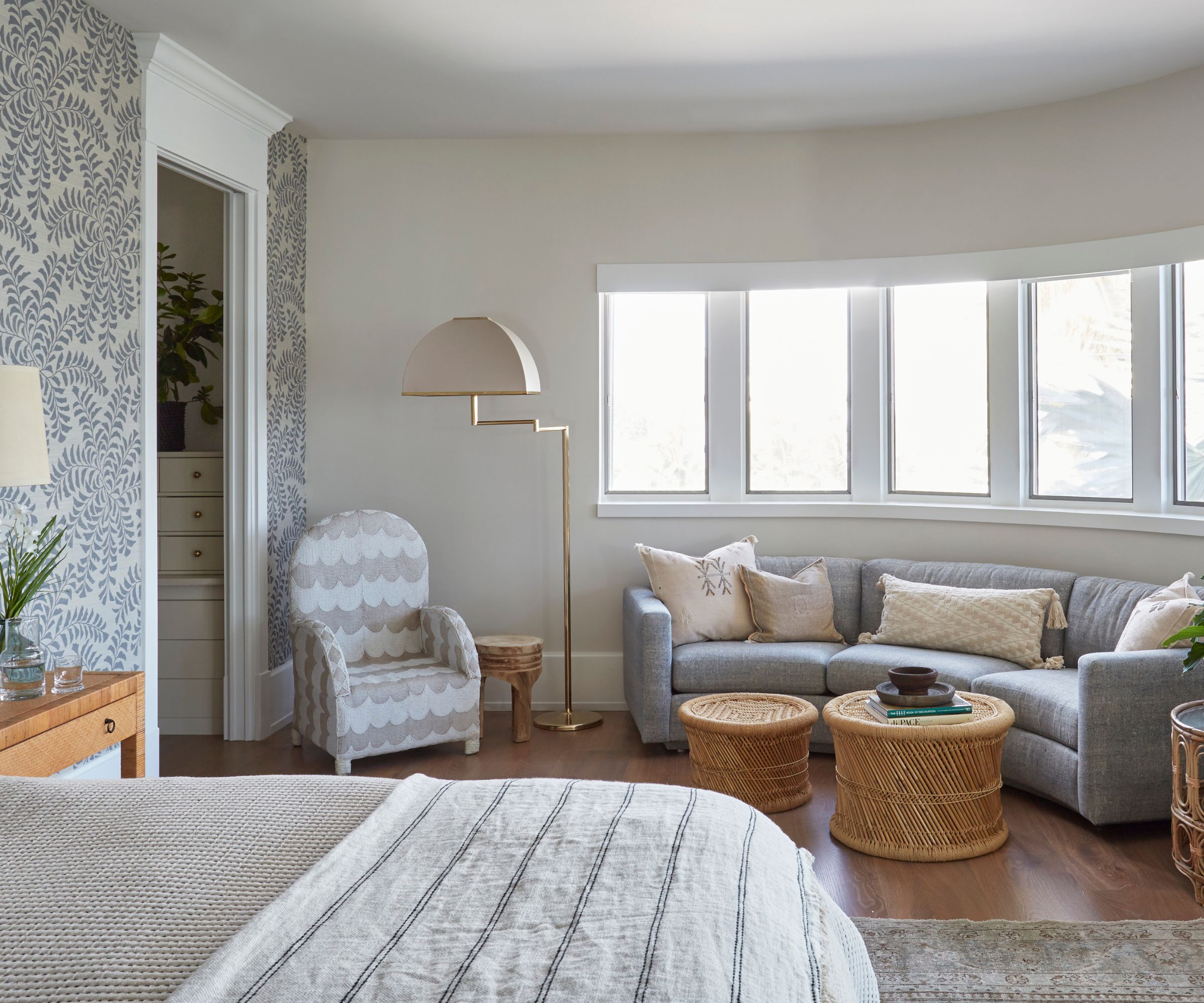 bedroom with white walls, a gray sofa by the windows and a patterned wallpapered wall