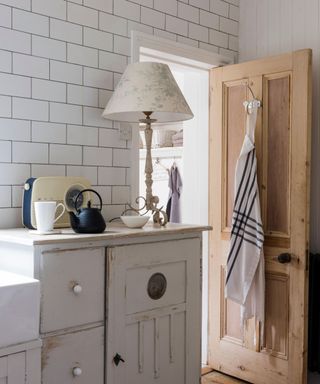 A side kitchen with a white and blue apron haning form a hook on the open door