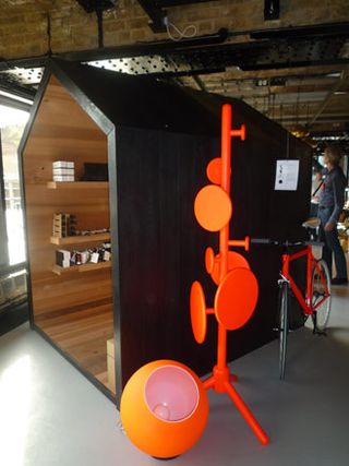 A Black house installation to display products by Sort of Coal, with an orange peg coat stand and bicycle next to it