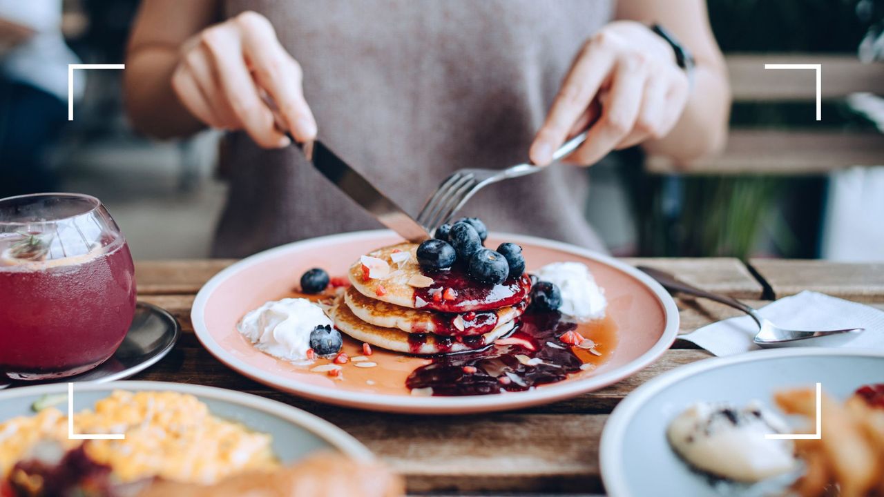 Healthy brunch pancakes covered in berries, sitting next to fruit juice