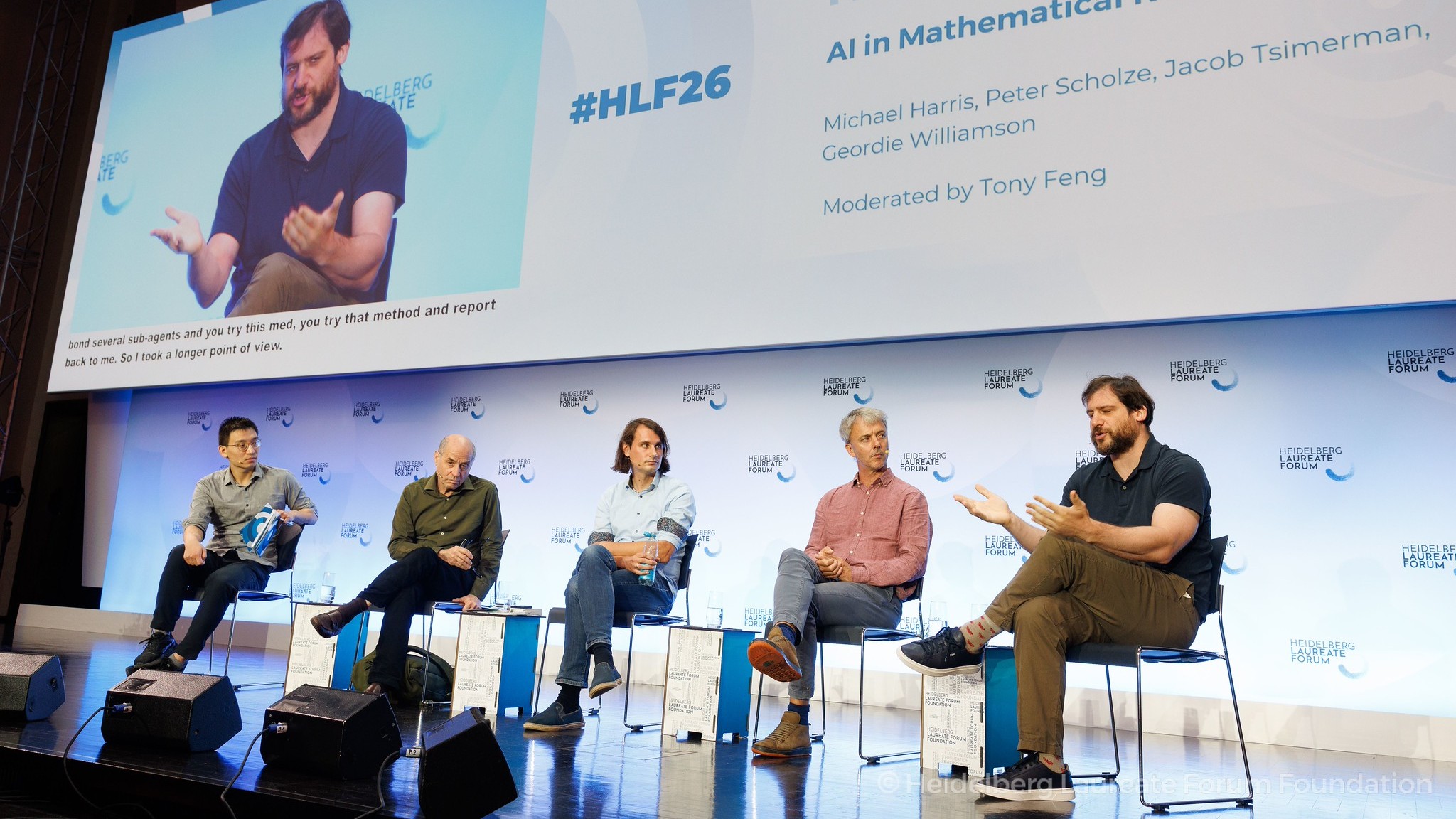 Five men sit on stage in front of a screen displaying the Heidelberg Laureate Forum 2026.