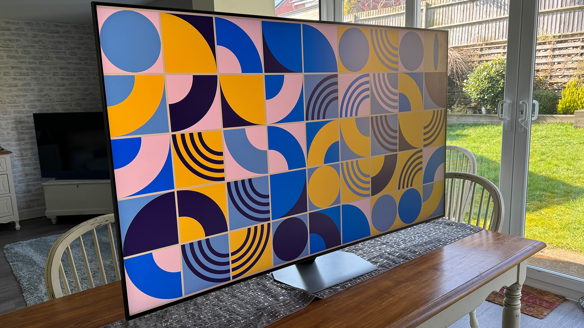 Samsung QN90F Mini LED TV on dining table with colourful pattern on screen