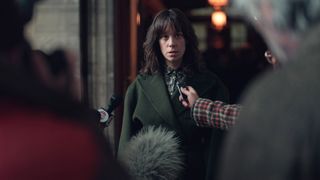 A still from episode 6 of Dept Q featuring a woman being interviewed by the press