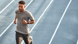 Man on a running track wearing Fitbit Versa 2 fitness tracker