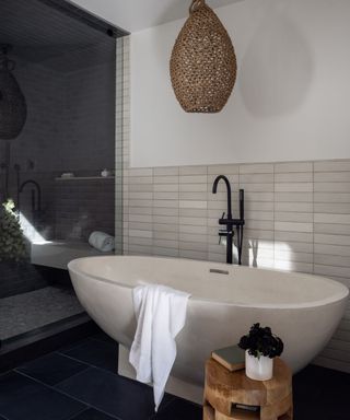 A California modern bathroom with a navy blue feature wall, a wooden side table and a rattan light fixture