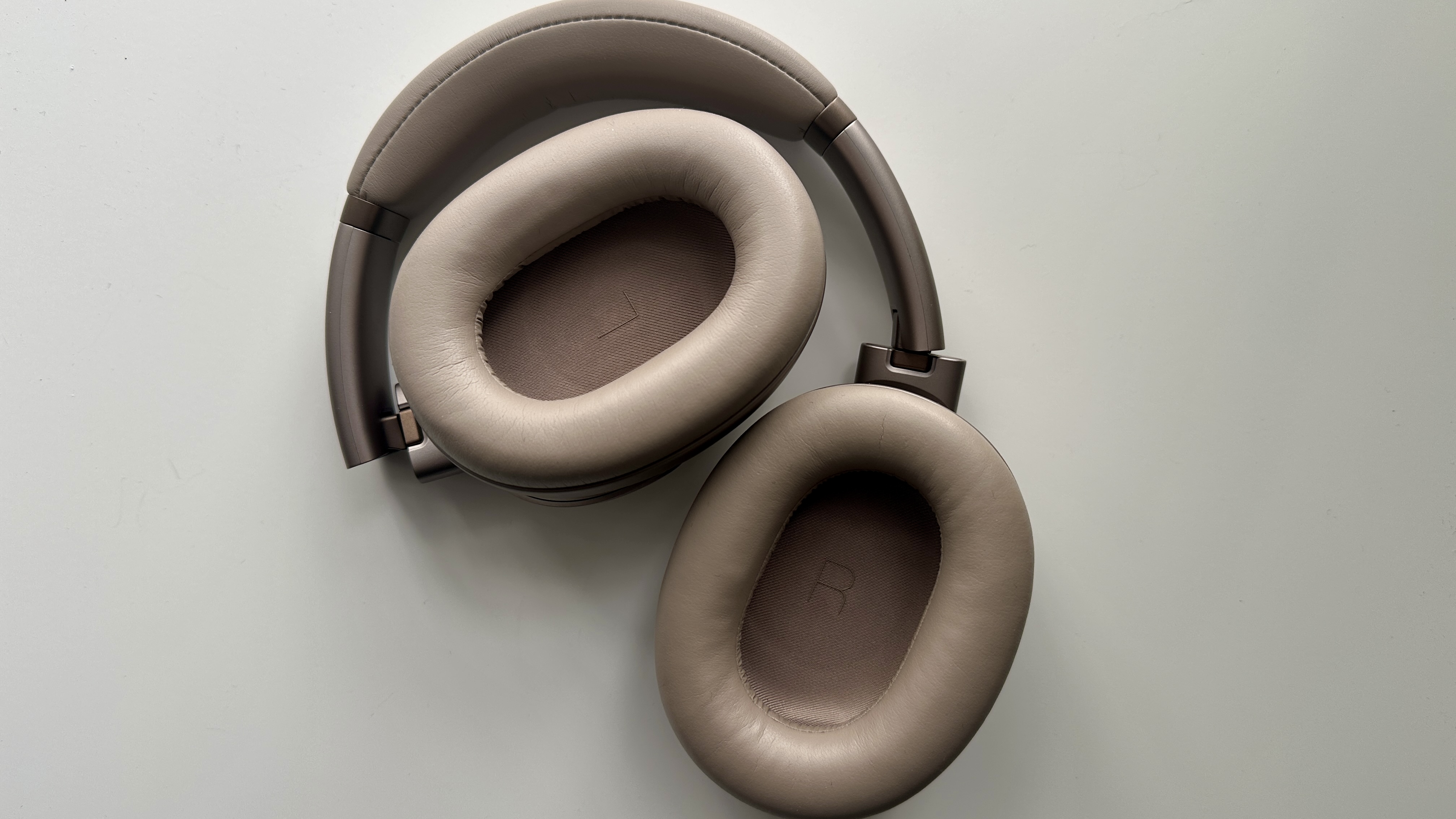Earcups of the JBL Tour One M3 over-ear headphones on a white surface