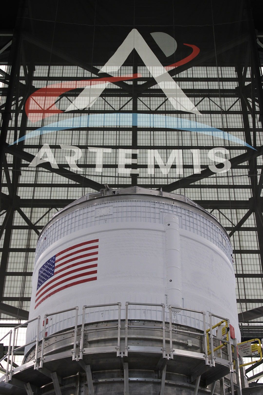 a large section of a rocket stands in a factory.