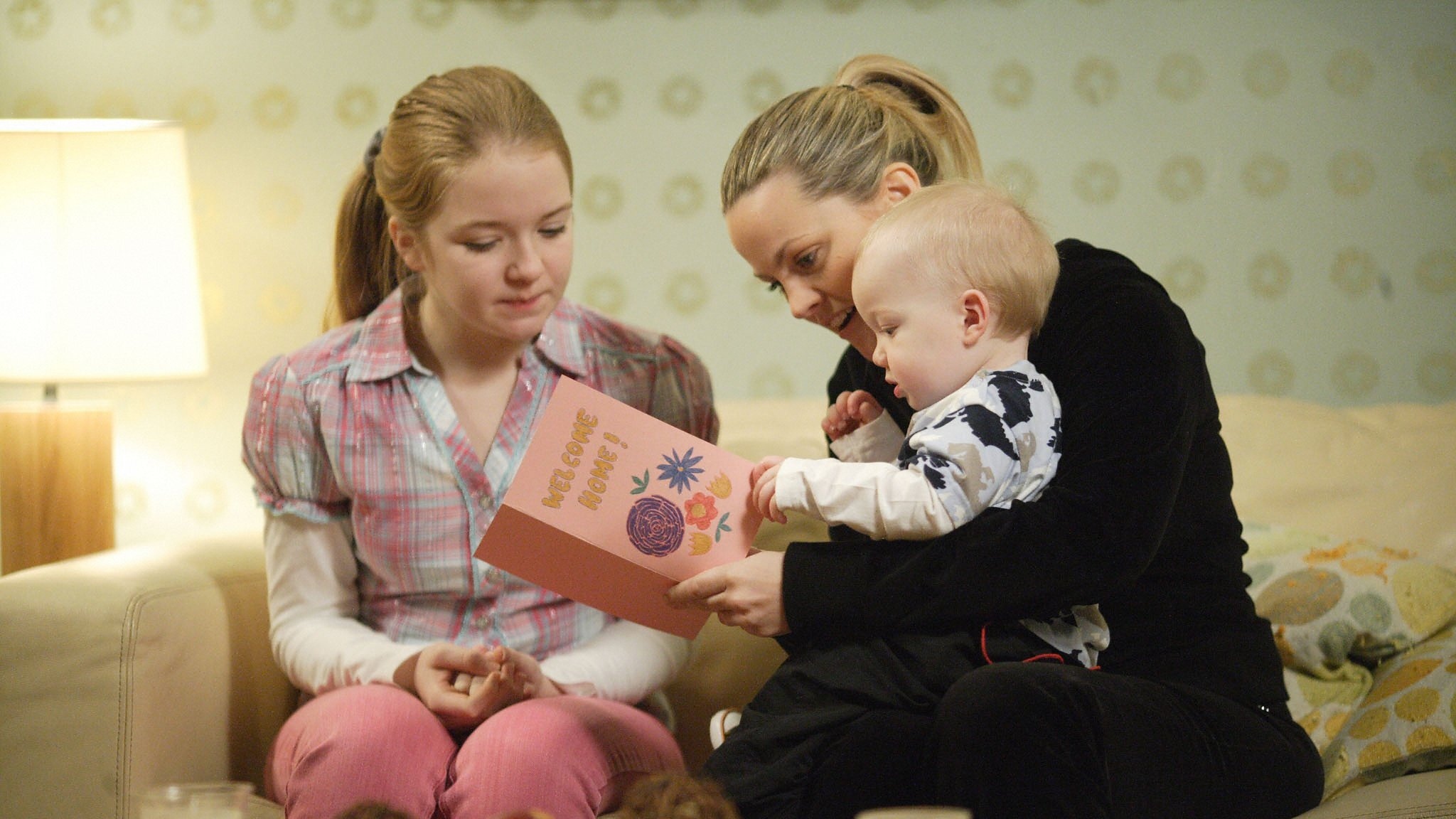 Tanya, Abi and Oscar read a Welcome Home card.