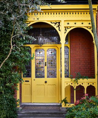Bright yellow front door and porch on brick house