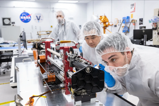 technicians in clean suits examine a drill in a clean room