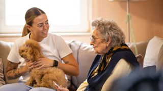 A young woman taking her dog to meet a senior citizen