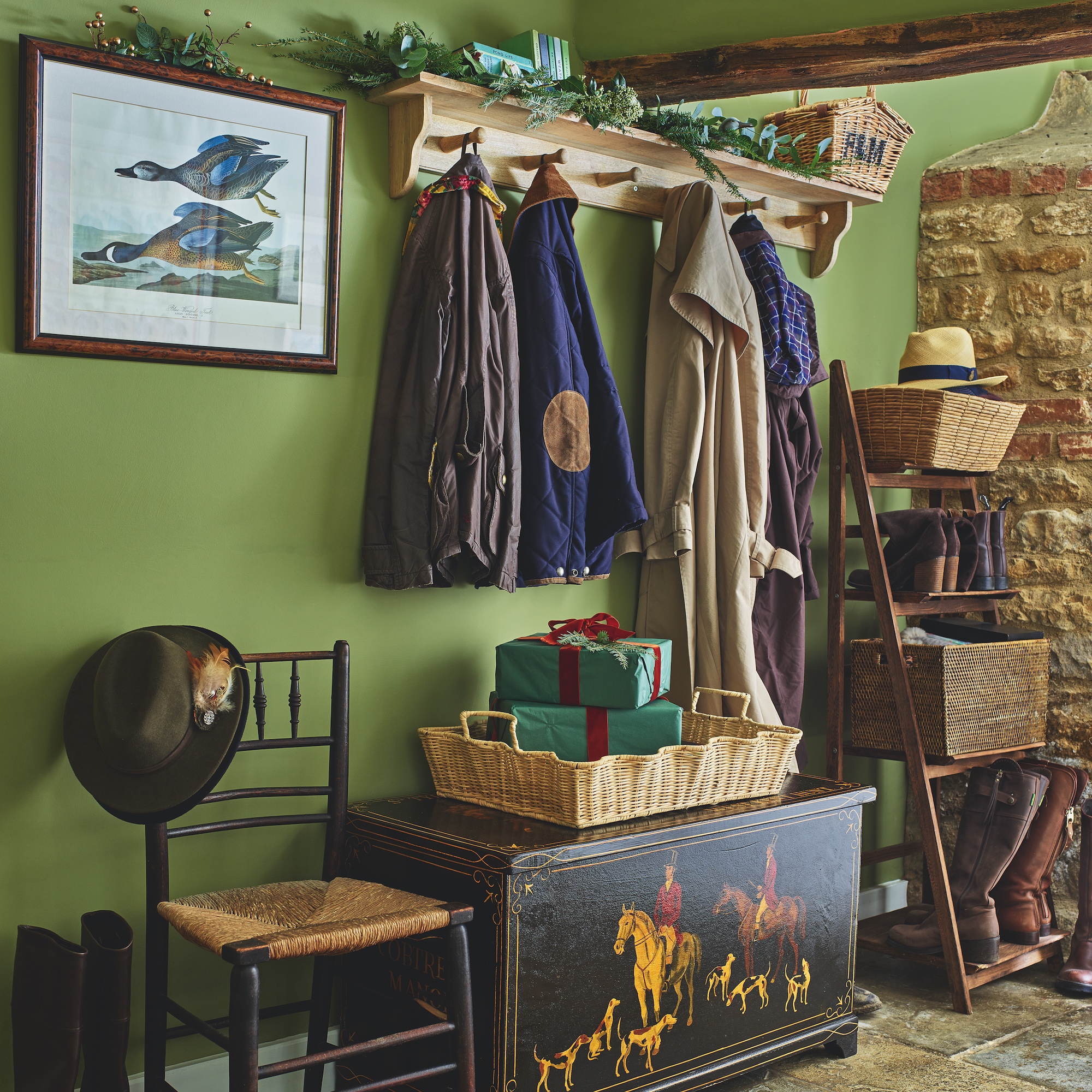 green painted hallway boot room with peg shelf for coats and antique wooden trunk with hunting scene