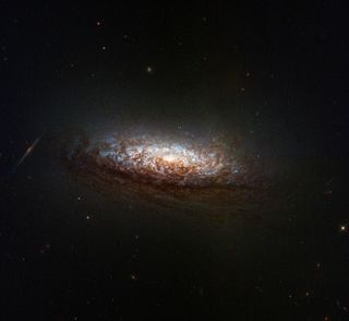 a stunning spiral galaxy hangs dimly in the dark of space; a bright light at its center illuminates nearby gasses, swirling around in shades of pale blues, whites and crisp browns.