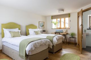 twin beds with green headboards in restored Welsh barn