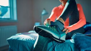 Woman wearing striped running socks putting on running shoes