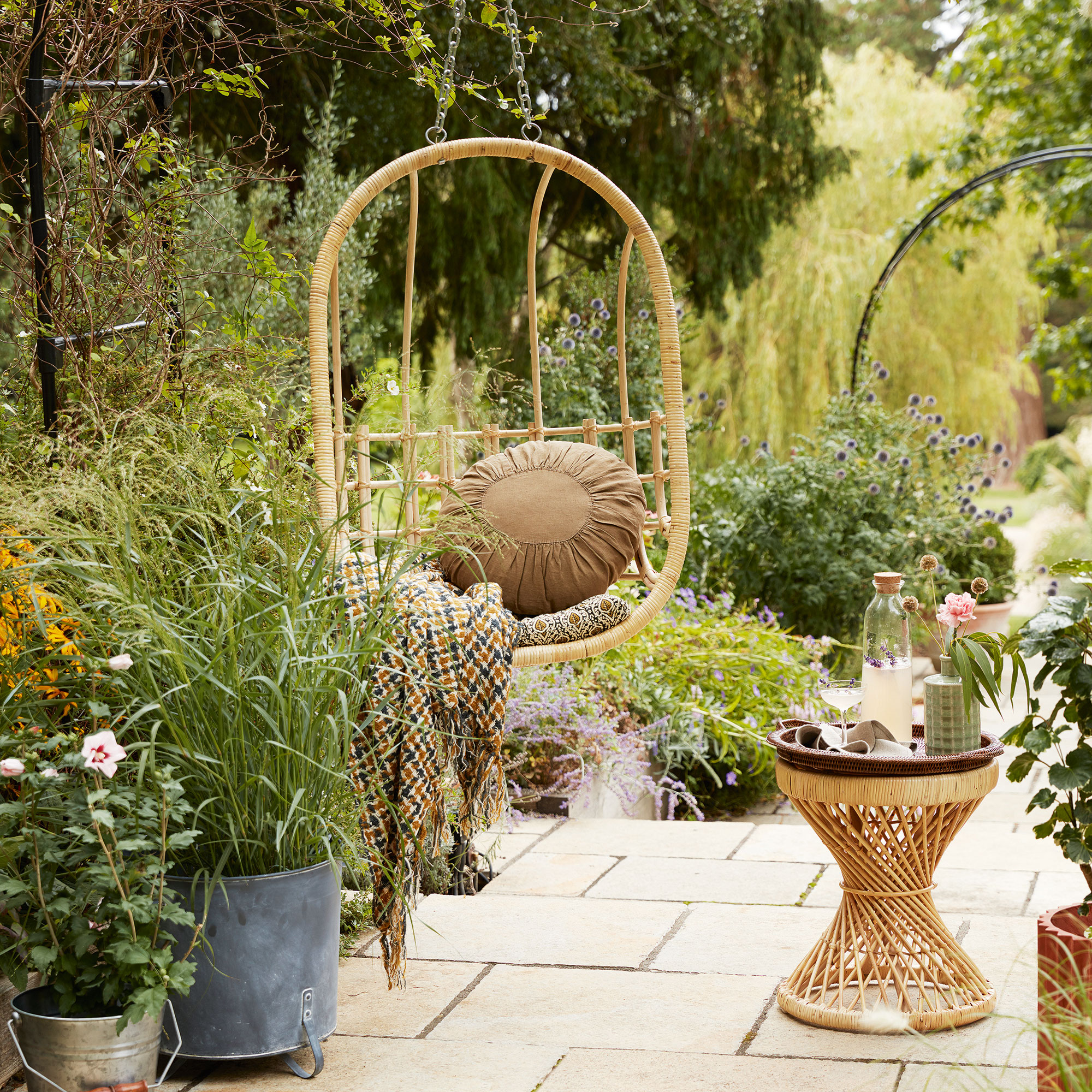 patio area with hanging chair and plants