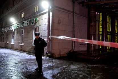 A Russian officer stands guard at the cite of a market blast in St. Petersburg.